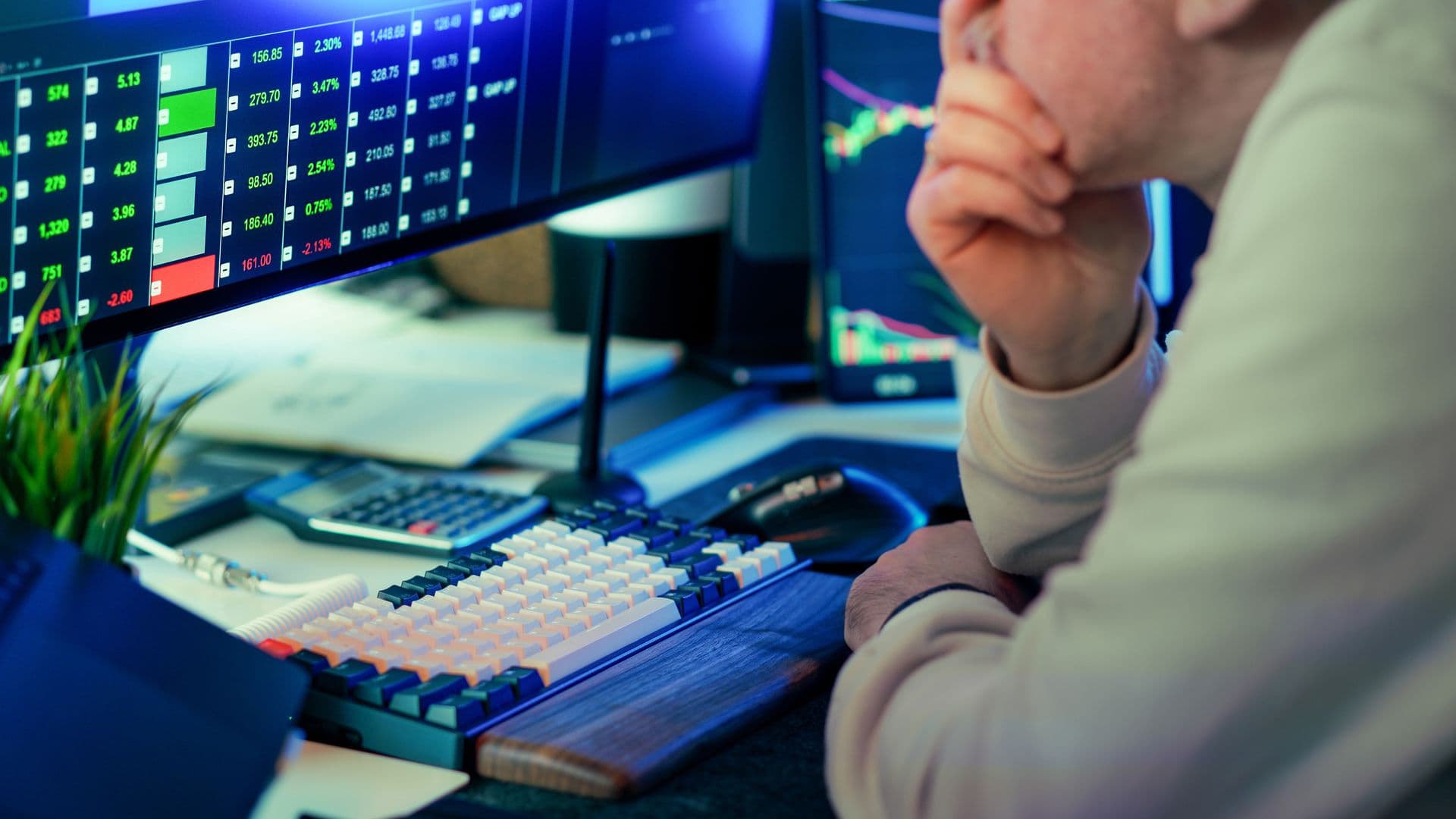 Market operator reviewing trading data on multiple screens